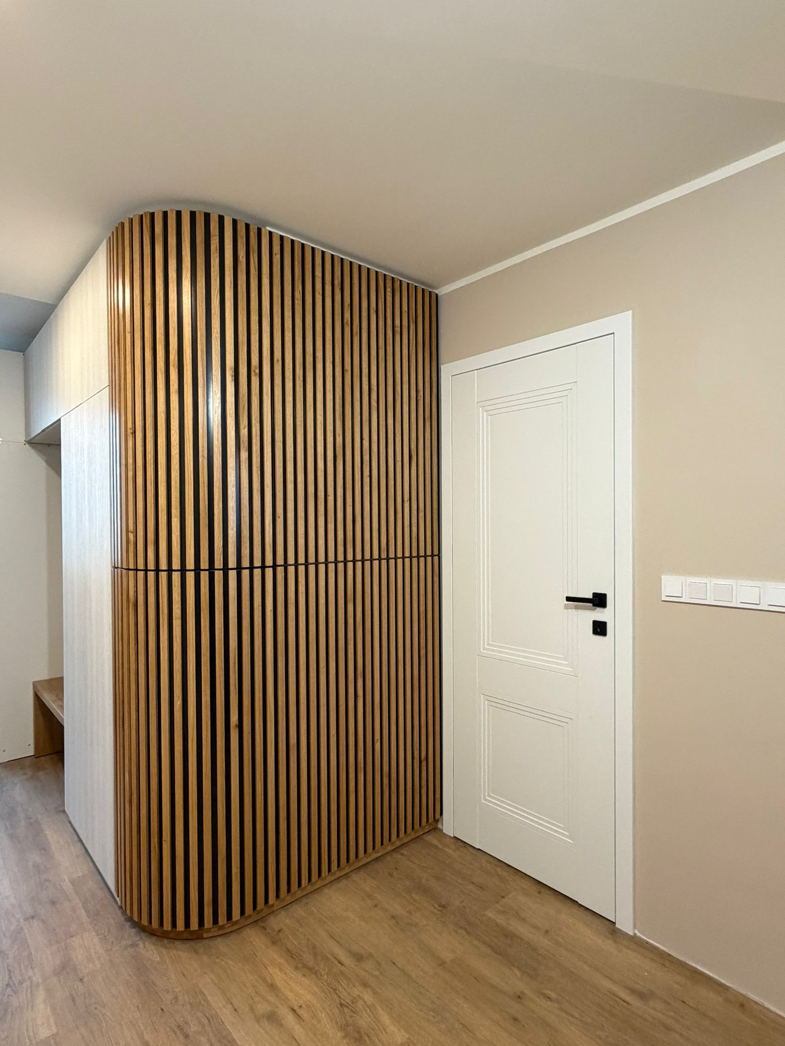 Dokončená moderní chodba s designovými dřevěnými lamelami a bílými dveřmi